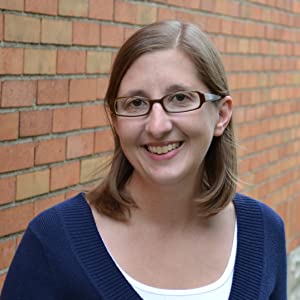 Woman in with glasses in front of brick wall