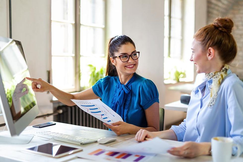 Coworkers smile at each other while working